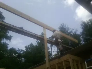 Carpenter setting a ridge beam over a new addition frame — Ice Dam Removal by Roofing Brothers in Oakland